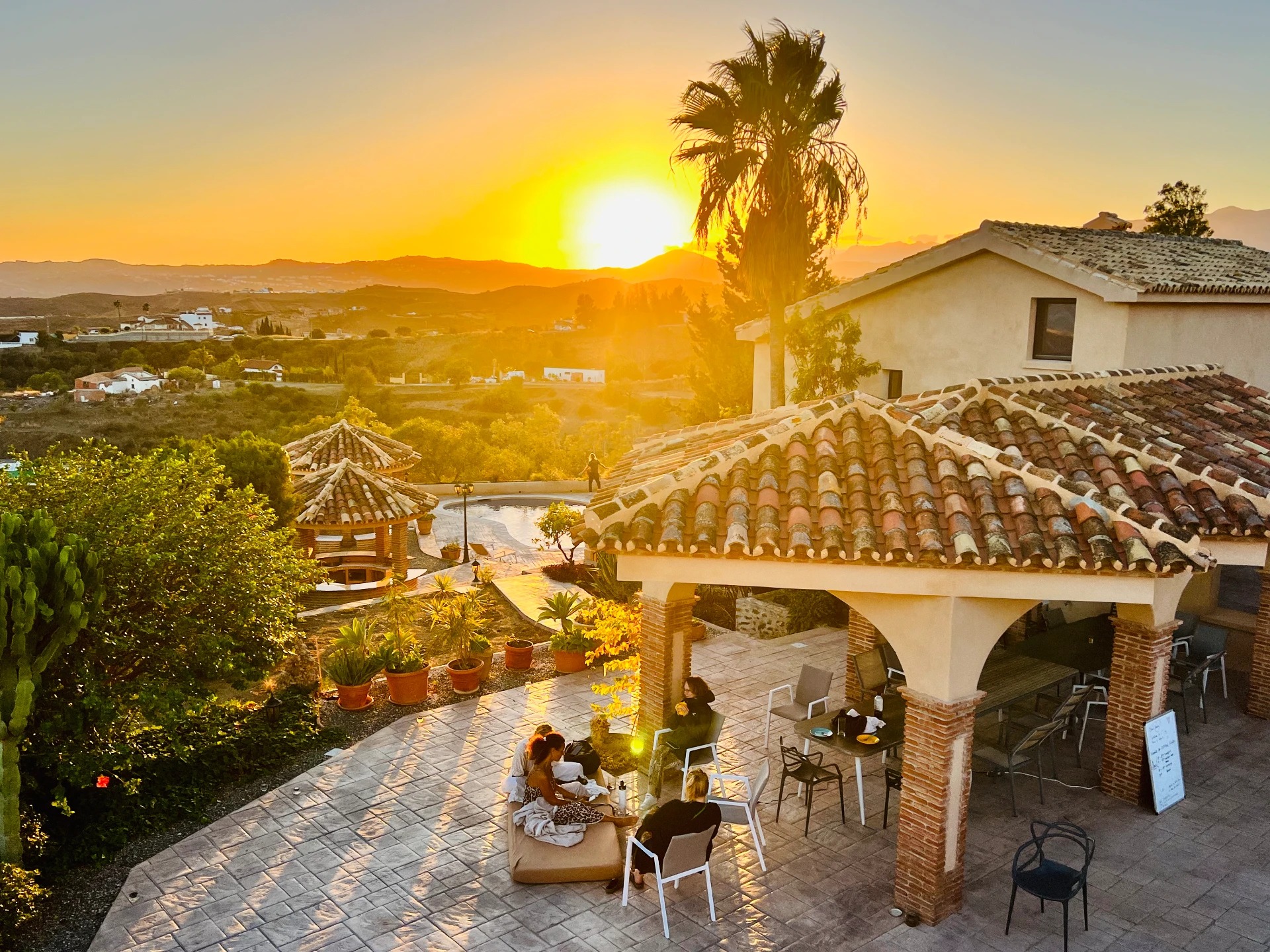 Golden sunset over the terrace, tiled rooftops and surrounding hills at House of Inquiry