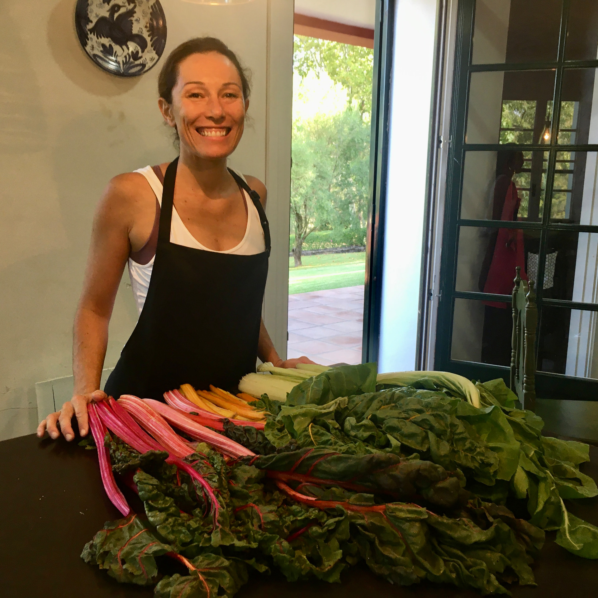 Danielle in her apron with a generous spread of freshly picked rainbow chard