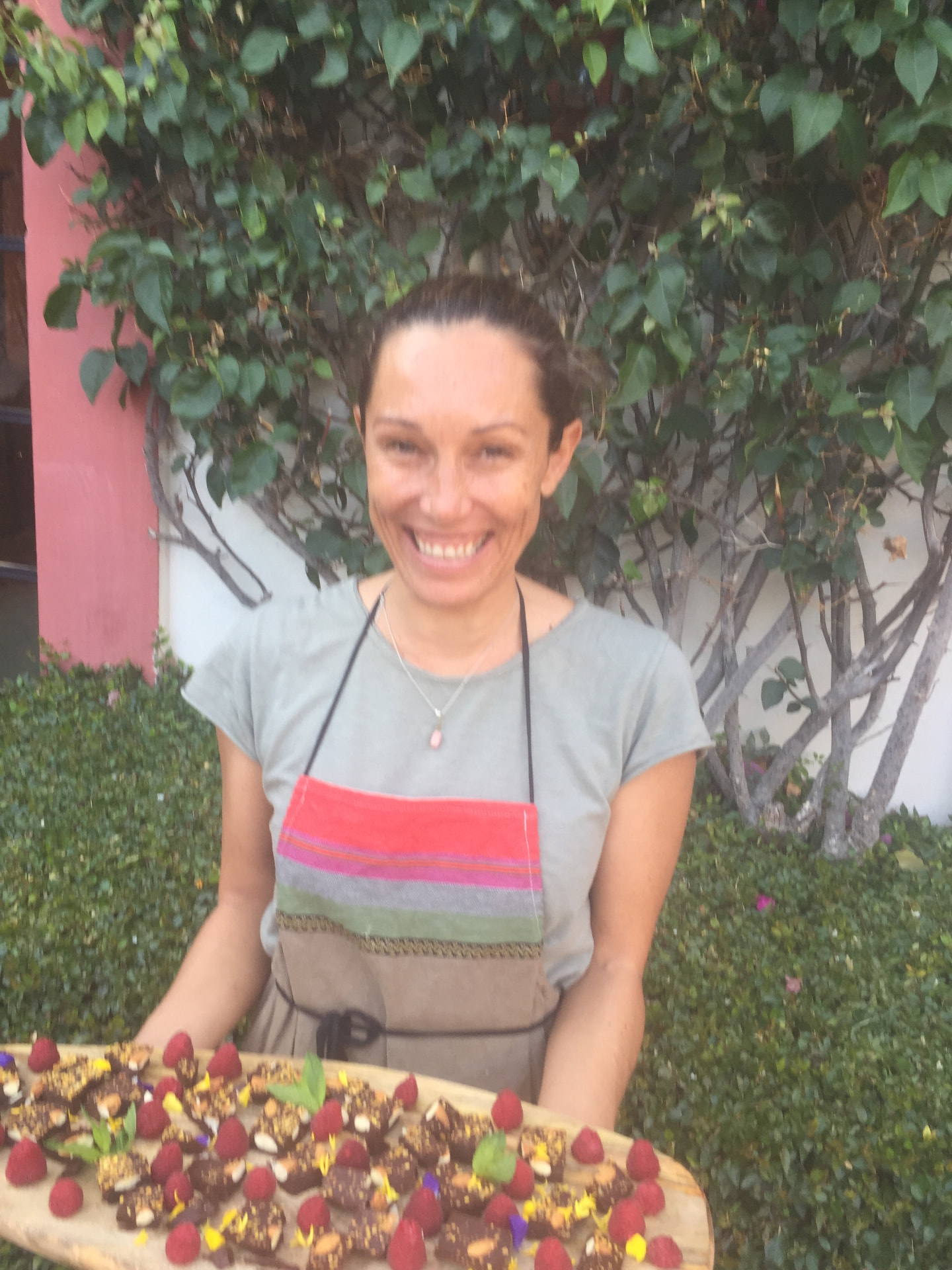 Danielle smiling while serving a platter of chocolate snacks topped with raspberries and flowers